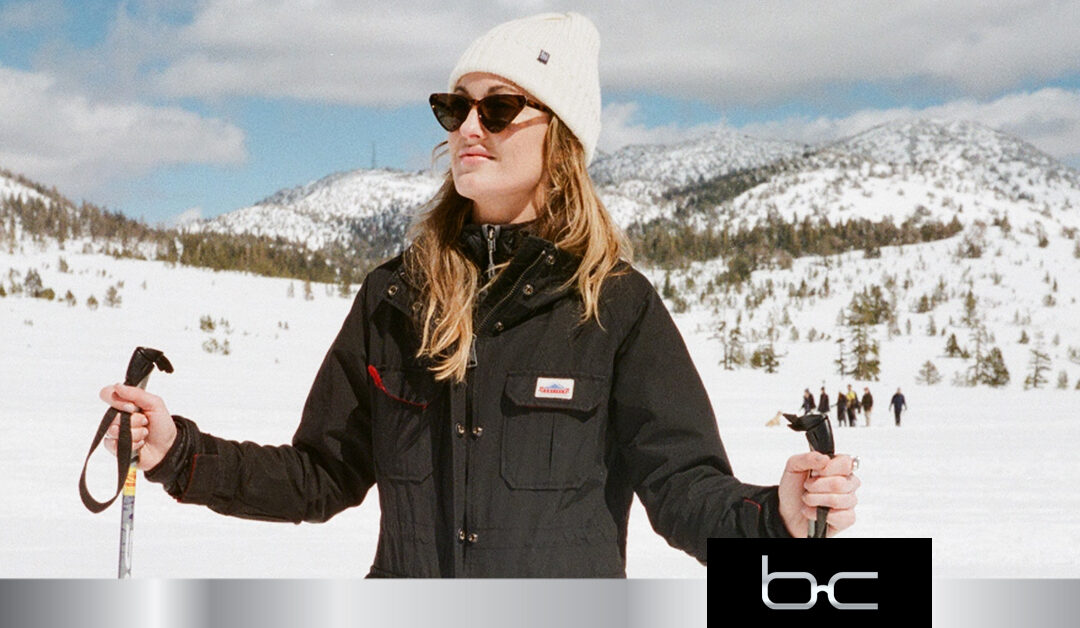 A woman skiier smiles in sunglassses.